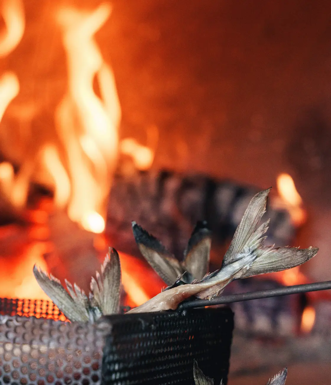 Two fresh fish in metal basket waiting to be cooked in Proper Kitchen's Wood fired oven